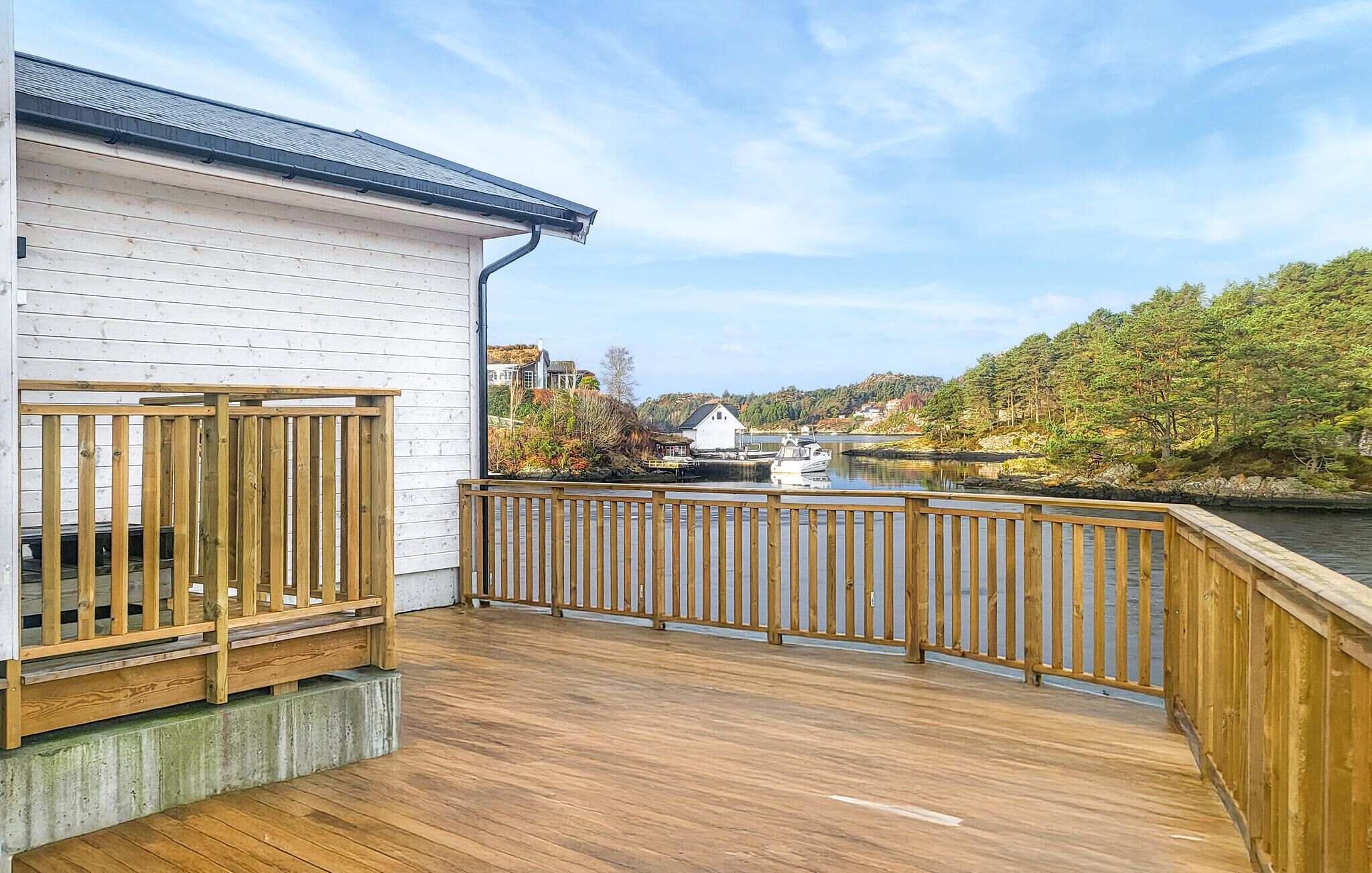Eine Holzterrasse mit Blick auf einen Fluss und ein weißes Gebäude.