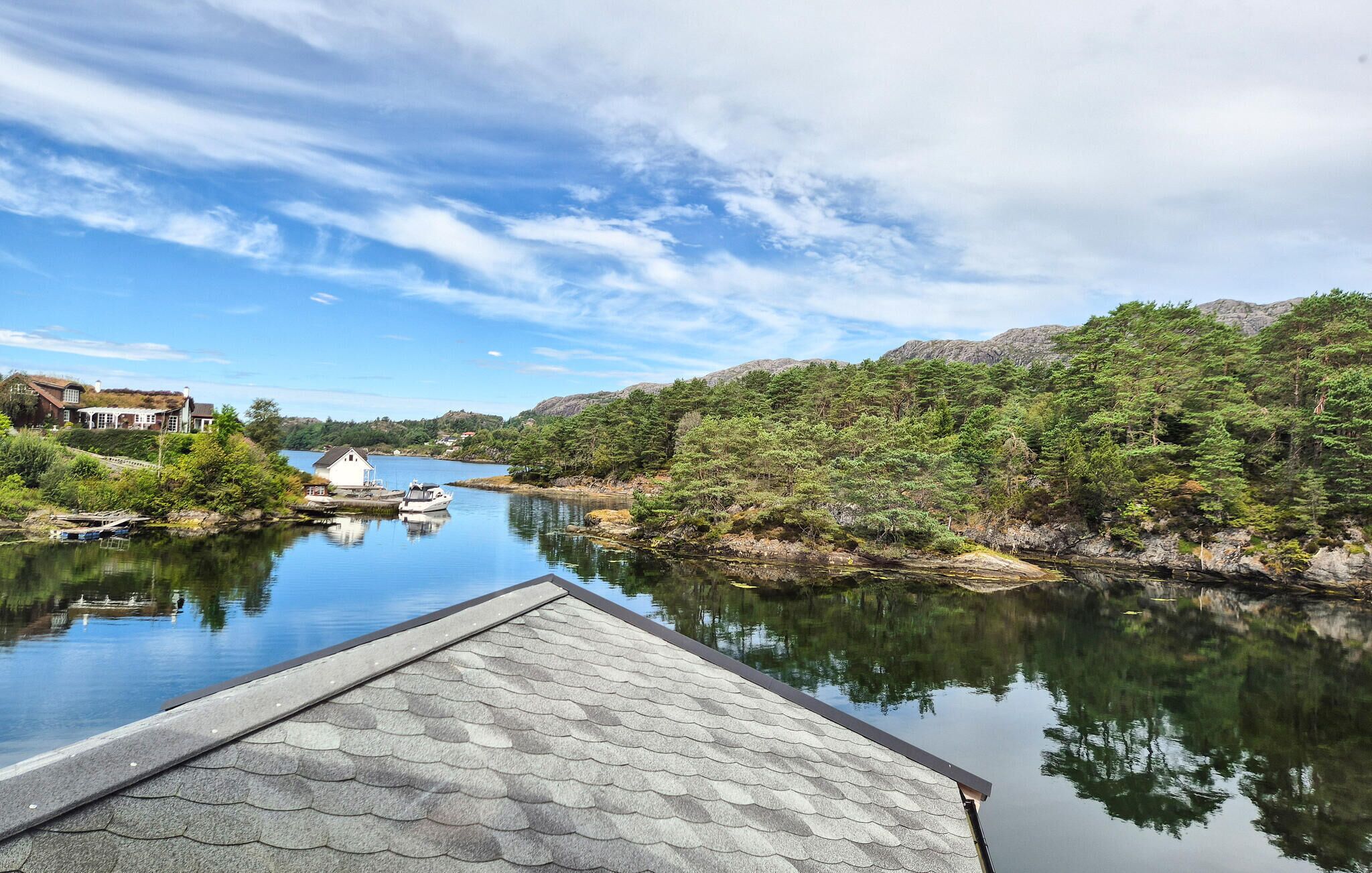 A calm lake with a dock, surrounded by dense forest and a mountain in the background.