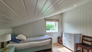 Une chambre à coucher comprenant un lit, une commode, une chaise et une fenêtre donnant sur un paysage verdoyant.