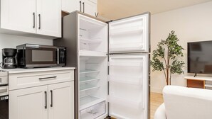 A modern kitchen with white cabinetry, a built-in microwave, and a large refrigerator. - Cozy & Spacious 2BR Guest Suite, Near Vancouver (Langley Township)