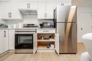 A modern kitchen with white cabinetry, a stainless steel refrigerator, a microwave, an oven, and a built-in dishwasher. - Cozy & Spacious 2BR Guest Suite, Near Vancouver (Langley Township)