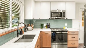 A modern kitchen with white cabinets, a stainless steel oven, and a microwave. - Modern Retreat w/ Hot Tub, Peloton, Gym, and BBQ (Westminster)