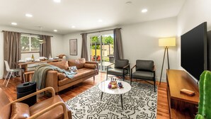 A modern living room with a sofa, chairs, a coffee table, and a TV. - Modern Retreat w/ Hot Tub, Peloton, Gym, and BBQ (Westminster)
