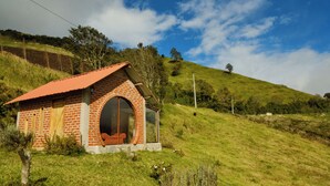 Une petite maison en briques avec un toit rouge, une grande porte d’entrée en arc de cercle et un petit porche.