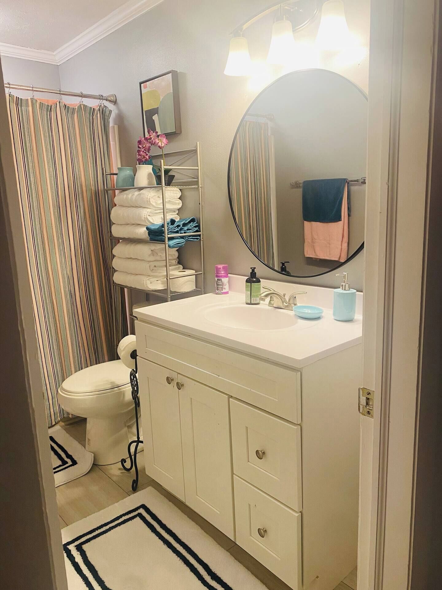 A bathroom with a white sink, a mirror, a toilet, and a shower curtain.