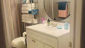 A bathroom with a white sink, a mirror, a toilet, and a shower curtain.