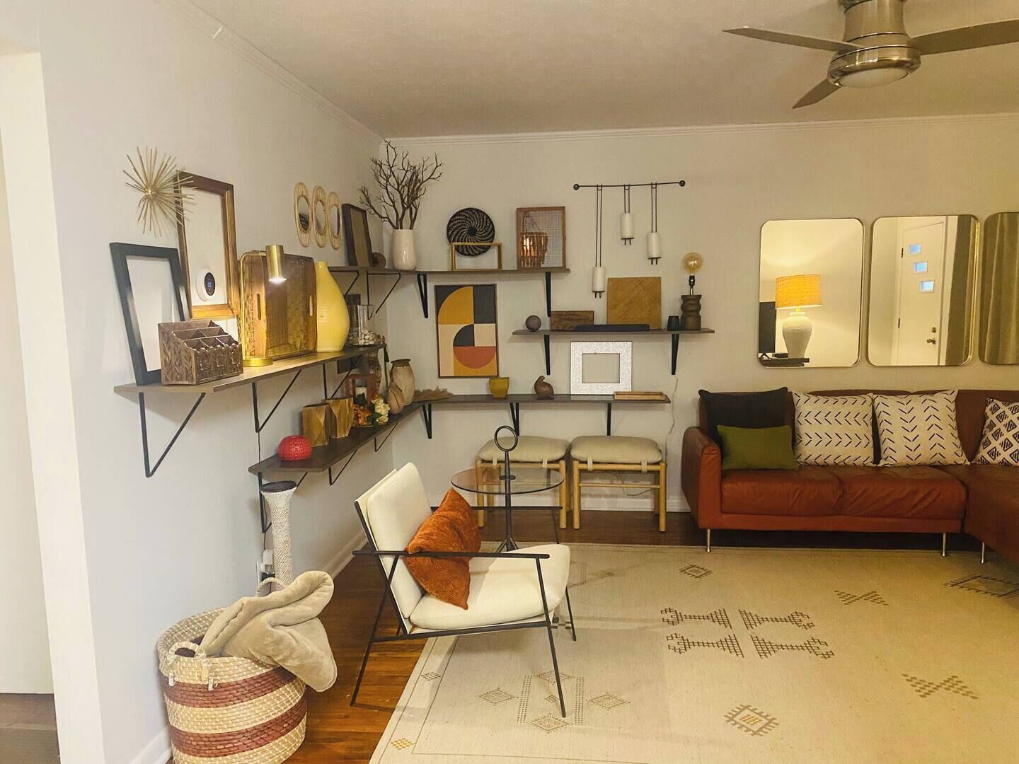 Ein Wohnzimmer mit einer Couch, Sesseln, einem Couchtisch und Regalen mit Dekoration.