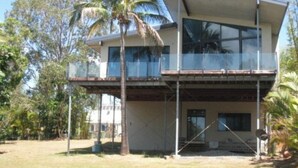 Uma casa de dois andares com uma varanda, cercada por árvores.