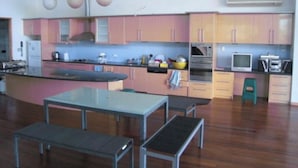 Uma cozinha moderna com armários rosa e amarelo, uma ilha central e um espaço de jantar com bancos.