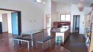 Um quarto espaçoso com piso de madeira, uma mesa de jantar com bancos, uma área de cozinha e um banquinho.