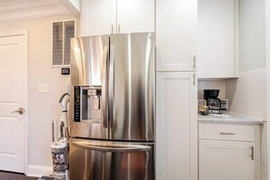 A stainless steel refrigerator with a water dispenser, a coffee maker, and a small cabinet in a kitchen with white cabinetry. - Entire DC Home + Private Suite Near Metro (Washington)