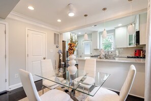 A modern kitchen with a glass dining table, white chairs, and pendant lighting. - Entire DC Home + Private Suite Near Metro (Washington)