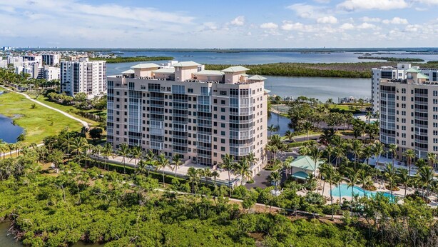 A high-rise hotel with multiple floors, surrounded by lush greenery and a body of water. - Heated Pool, Sauna,| 3BR Condo| Waterside #835 (Fort Myers Beach)