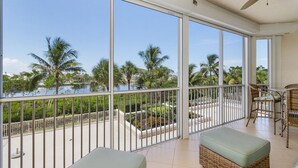 A balcony with a view of palm trees and a body of water. - Heated Pool, Sauna,| 3BR Condo| Waterside #835 (Fort Myers Beach)