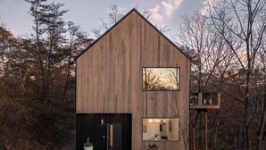 A modern wooden cabin with a large window, a balcony, and a door. - Pool + Hot Tub + Plunge | Scandinavian Wellness Retreat (Weaverville)