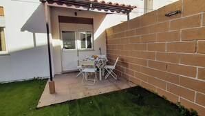 A small patio with a table and chairs, a door, and a brick wall. - 2-bedr. house in the tranquillity of Azeitão. (Vendas de Azeitão)