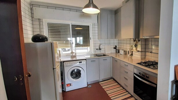 A compact kitchen with a washing machine, a stove, and a sink. - 2-bedr. house in the tranquillity of Azeitão. (Vendas de Azeitão)