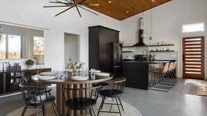 A modern kitchen with a central island, black cabinetry, and a stainless steel refrigerator.