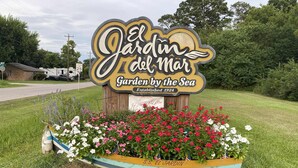 A garden sign for 'El Jardin del Mar' with a boat-shaped planter filled with flowers. - Charming 3-bedroom cottage in Seabrook, Texas (Seabrook)