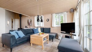 A cozy living room with a sofa, a coffee table, a TV, and a window with curtains.