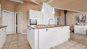 A modern kitchen with wooden paneling, a central island with a dishwasher, a built-in oven, and a sink.