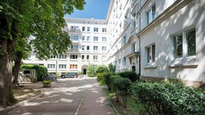 En boligbeliggende gade med fortov, et træ og en bygning med flere vinduer og altaner.