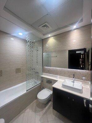 Een aparte badkuip en douche, een haardroger, pantoffels, handdoeken