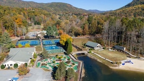 An aerial view of a resort with tennis courts, a swimming pool, and a bridge connecting different areas. - The Ginger Fox Log Cabin w/ Resort Perks | Lake Lure (Lake Lure)