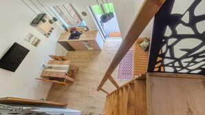 A modern interior with a wooden staircase, a dining area, and a view of the outdoors.