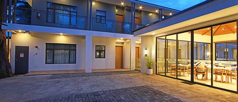 A modern two-story building with a covered outdoor seating area and a glass facade.