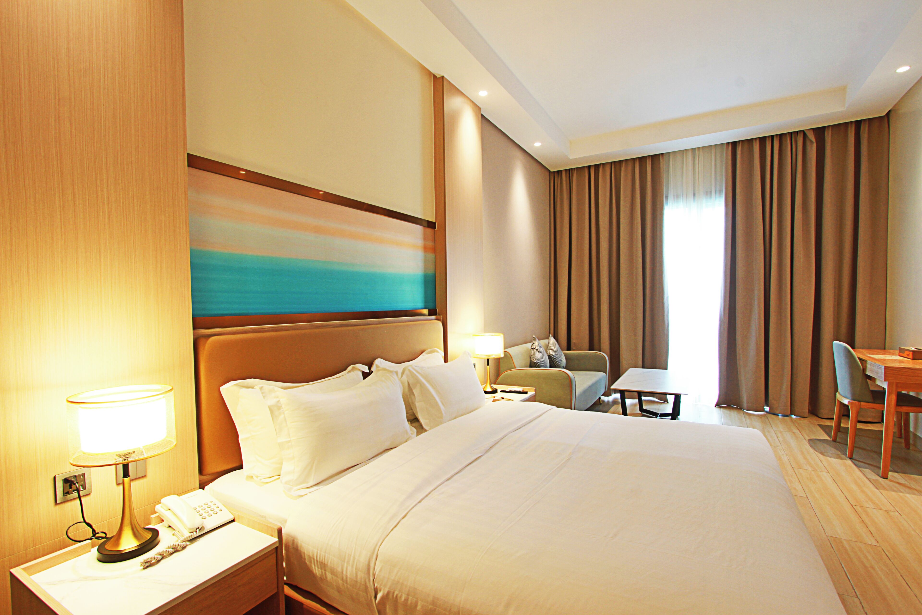 A hotel room with a large bed, bedside tables, a desk, and a chair.