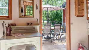Eine Küche mit Fenster, Spiegel, einem kleinen Schrank und einem Essbereich mit Stühlen und einem Sonnenschirm.