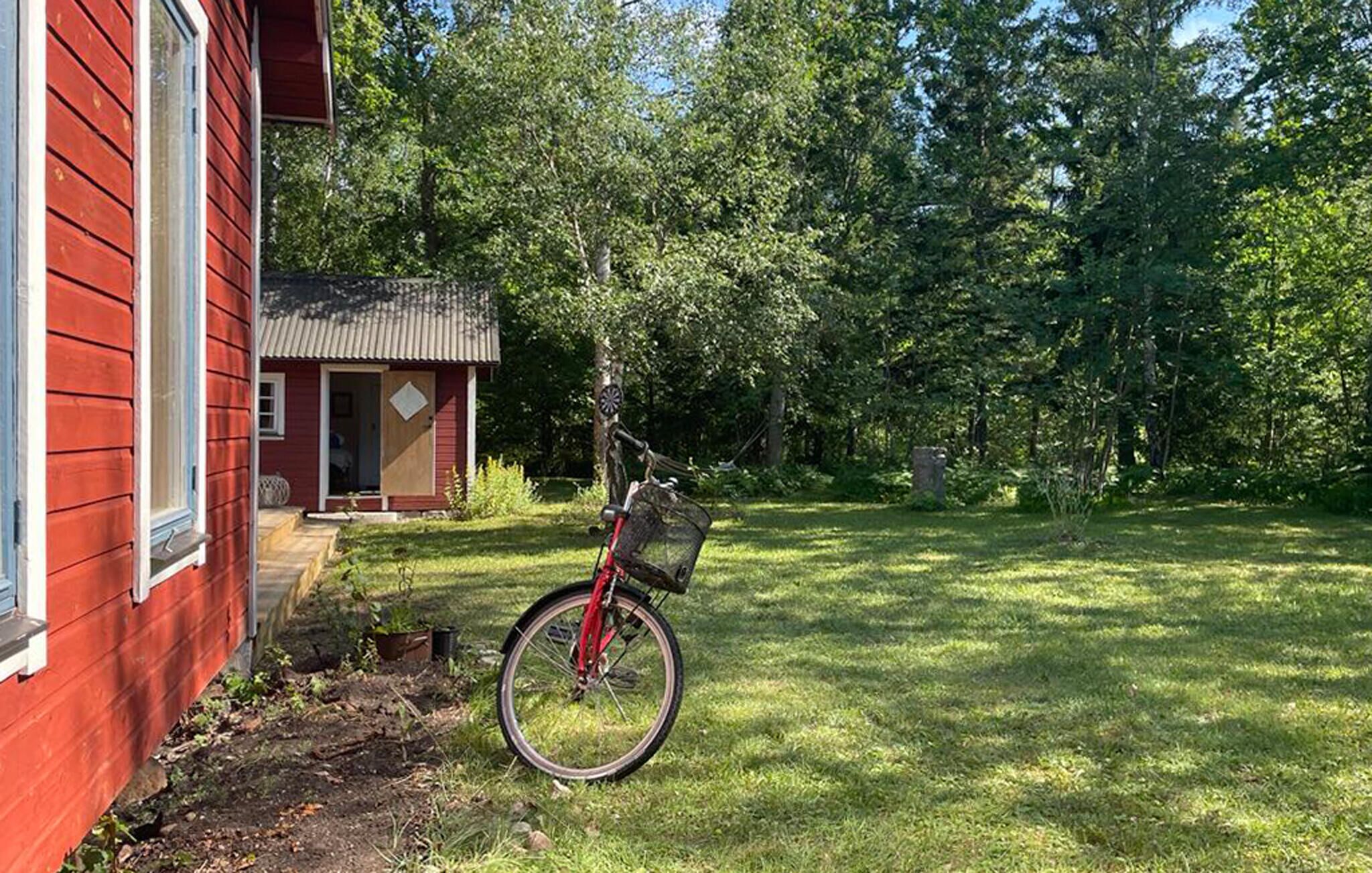 A red house with a small porch and a bicycle leaning against it.