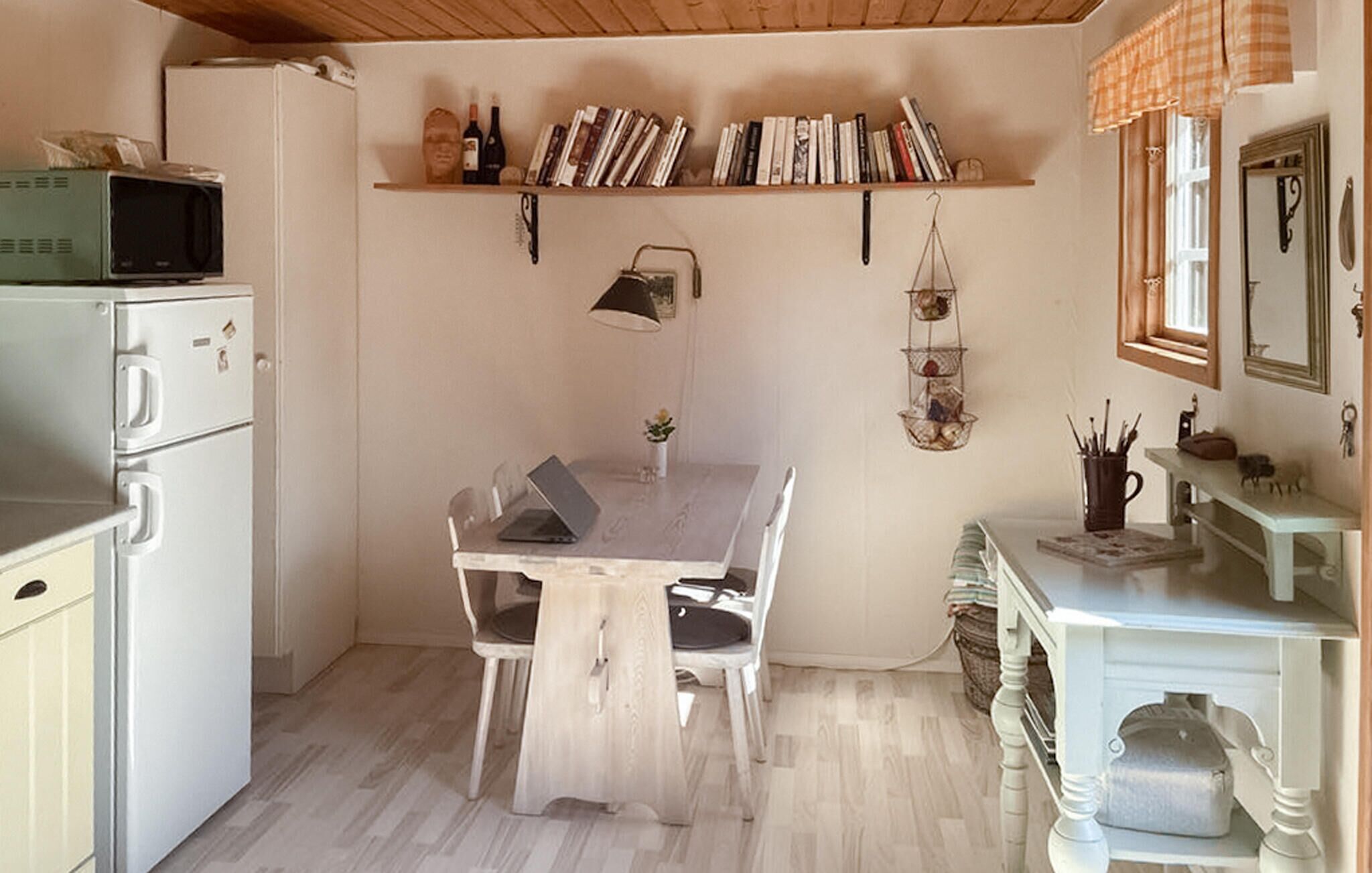 A compact kitchen with a dining table, white cabinets, a microwave, and a hanging light fixture.