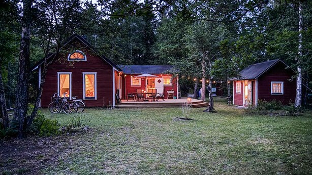 Eine rustikale Holzhütte mit Veranda, Essbereich und einem kleinen Nebengebäude.