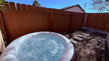 Een hottub in een achtertuin met een houten schutting en een laagje mulch.