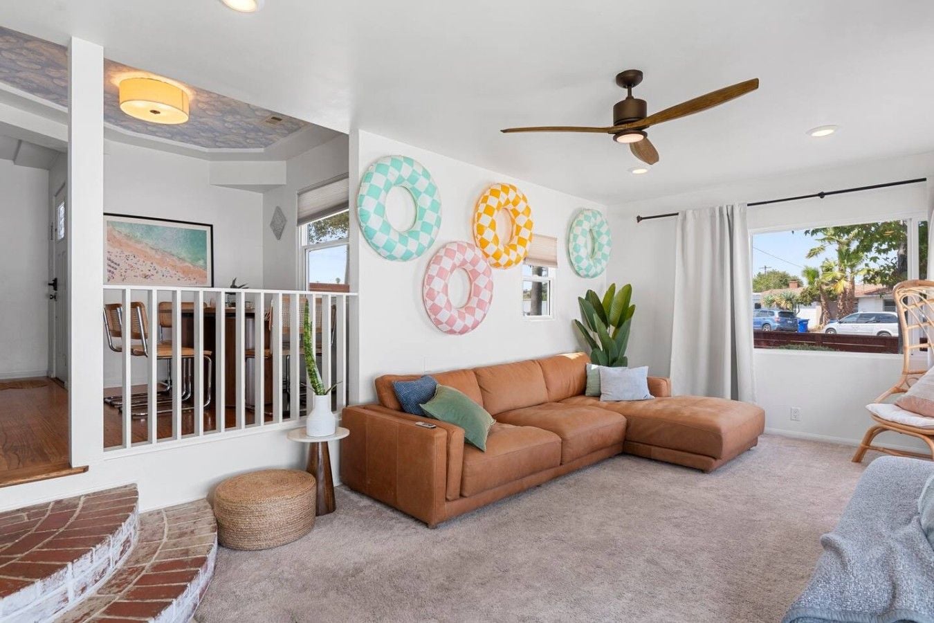 A modern living room with a sectional sofa, a ceiling fan, and decorative wall art.