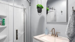 Une salle de bain avec une douche à parois de verre, un lavabo doté d’un robinet moderne et un miroir au-dessus du lavabo.