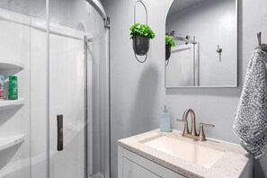 Een badkamer met een douchecabine van glas, een wastafel met een moderne kraan en een spiegel boven de wastafel.