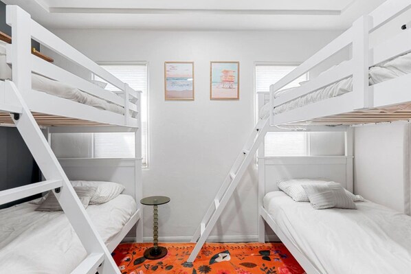 A bunk bed room with two beds, a small round table, and a colorful rug.