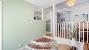 A staircase with a brick design leading to a dining area with wooden furniture and a ceiling light.