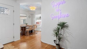 Un couloir orné d’un panneau néon sur lequel on peut lire « Sunshine » et d’une plante en pot.