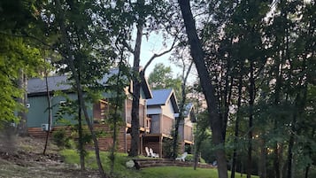 A cabin with a wooden exterior, surrounded by trees and a grassy area.