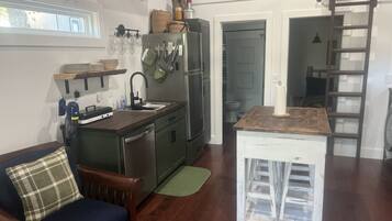 Une cuisine compacte avec une table à manger en bois, un évier encastré et un petit îlot central.
