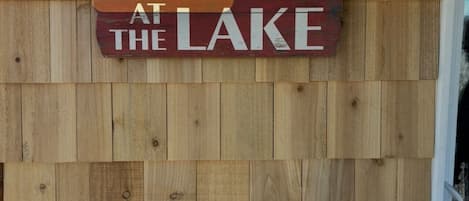 Een houten wand met een bord waarop staat: LIFE IS BETTER AT THE LAKE.