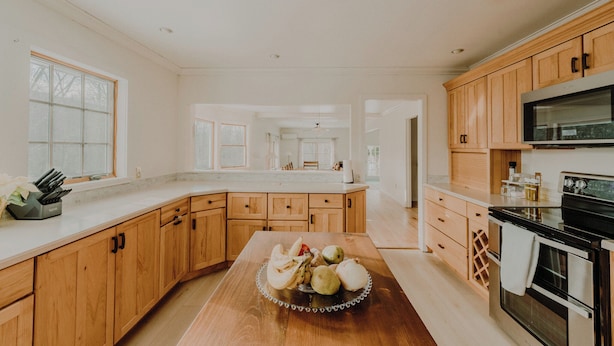 A spacious kitchen with wooden cabinets, a large island, and a stainless steel oven. - Group Getaway: Sleeps 15, 11 Priv Acres, Wood fire hot tub, sauna, karaoke (Margaretville)
