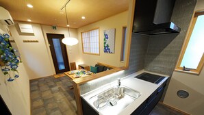 Una cocina moderna con una isla central, estufa integrada y un lavabo. Hay una zona de comedor con una mesa y sillas, y una pared decorativa con un estampado floral.
