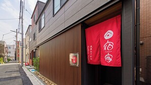 Un edificio moderno con fachada de madera y un cartel rojo con el logotipo de Yadoya.