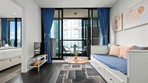 Een moderne kamer met een bed, een slaapbank, een tafeltje en uitzicht door een glazen deur.