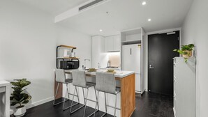 Een moderne keuken met een centraal eiland, barkrukken, een magnetron en een koelkast.